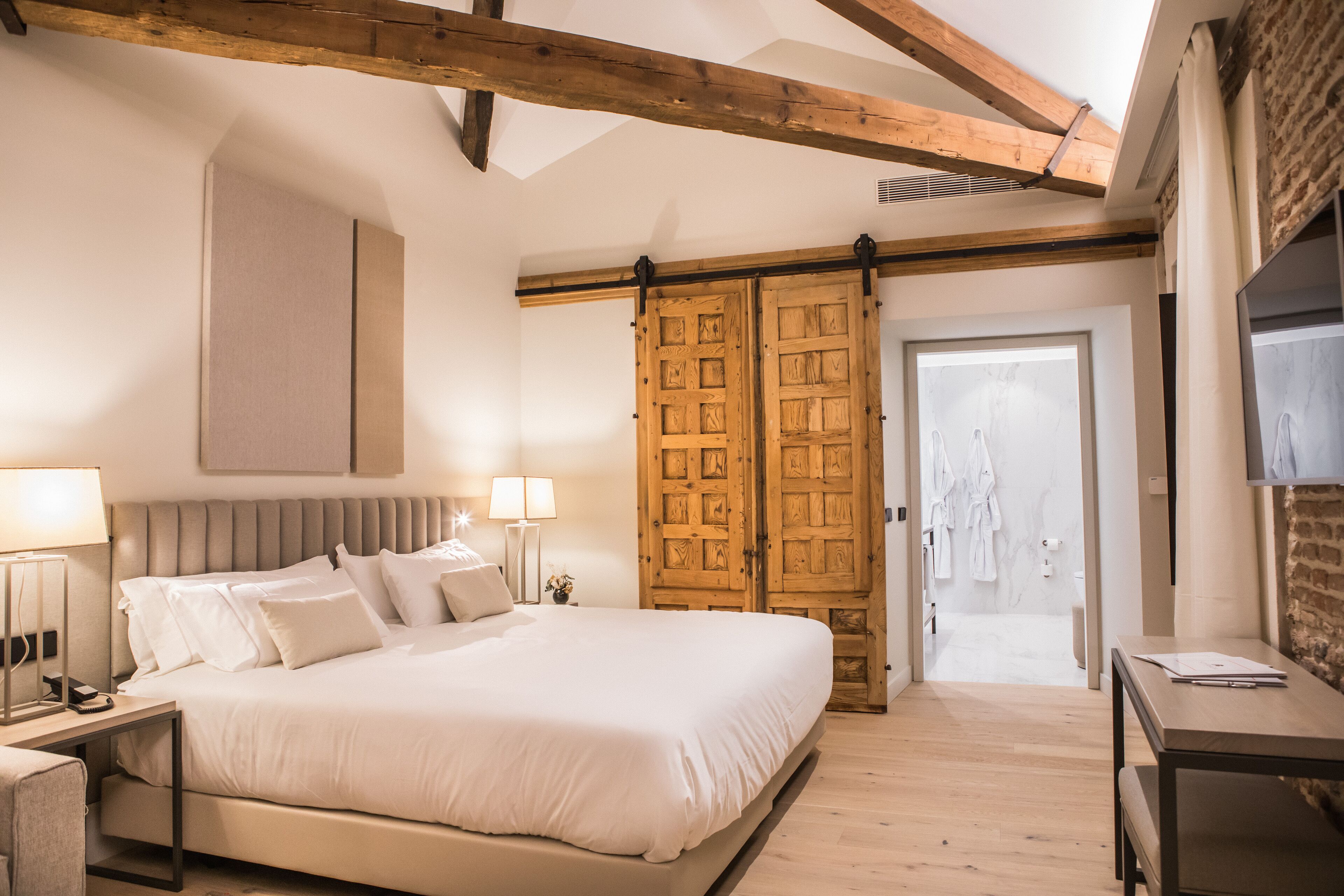 Un dormitorio con una cama grande, un armario de madera y un escritorio con lámpara.