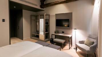 A bedroom with a bed, a desk, a chair, a wardrobe, and a TV.