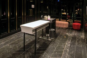 Un bagno moderno con un lavandino bianco, pavimento in marmo nero e un cestino.