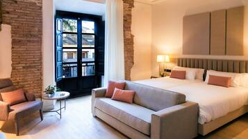 Een moderne hotelkamer met een groot bed, een bank, een tafeltje en uitzicht naar buiten.