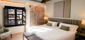 Una camera da letto con un letto grande, una finestra che offre vista su edifici, un muro in mattoni e una lampada moderna.
