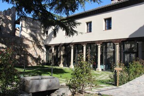 Un cortile con colonne in pietra, una fontana e un edificio con ampie finestre.