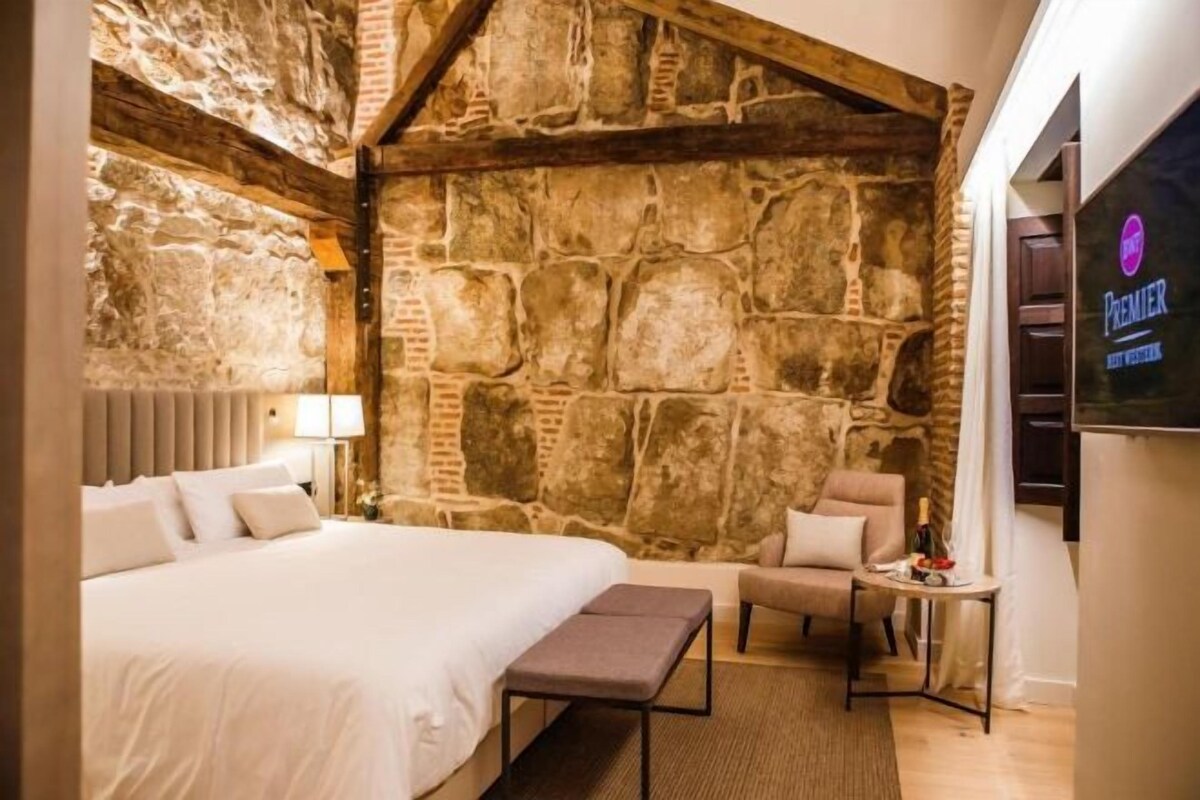 Ein Schlafzimmer mit Stehwand, einem Bett, einer Bank und einem kleinen Tisch mit Lampe.