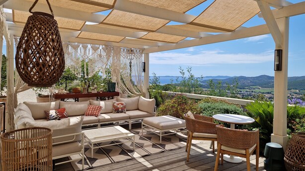 A covered outdoor seating area with a sofa, chairs, and a table, overlooking a scenic landscape. - Eden Rose Grand Hotel, BW Premier Collection (Bormes-Les-Mimosas)