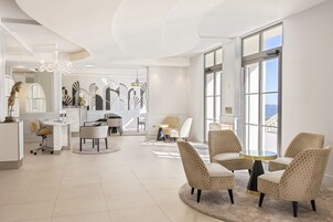 Un vestíbulo de hotel moderno con una mesa redonda, asientos cómodos, una recepción y ventanas amplias que ofrecen vistas.