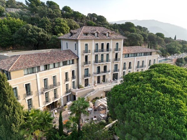 A multi-story hotel with balconies, a courtyard with outdoor seating, and a pool area.