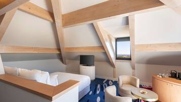 Una habitación de hotel moderna con un entrepiso para dormir, un televisor de pantalla plana, una pequeña mesa y vistas al exterior.