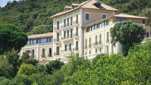 A multi-story building with balconies, surrounded by lush greenery and hills. - Eden Rose Grand Hotel, BW Premier Collection (Bormes-Les-Mimosas)