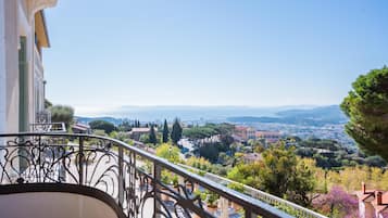 Ein Balkon mit schmiedeeisernen Geländern mit Blick auf eine malerische Stadt mit Häusern und Bäumen.