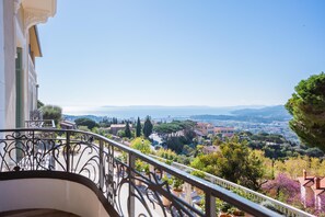 A balcony with wrought iron railings overlooking a scenic town with buildings and trees. - Eden Rose Grand Hotel, BW Premier Collection (Bormes-Les-Mimosas)