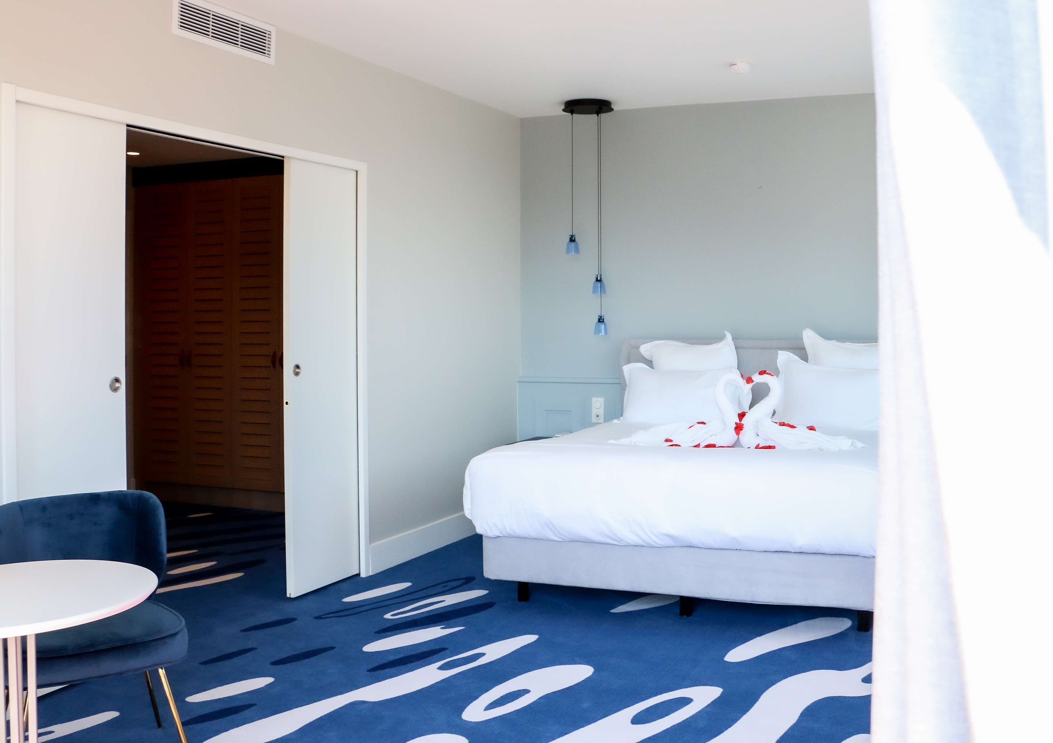 A hotel room with a bed, a desk, and a chair.