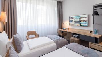 Ein Hotelzimmer mit Bett, Schreibtisch, Stuhl und einem Fernseher, der eine Speisekarte zeigt.