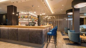 A modern bar area with a bar counter, multiple hanging pendant lights, and bar stools.