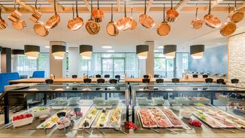 Ein Buffetbereich mit mehreren Speiseausgaben, hängenden Kupferkesseln und einem modernen Innenraumdesign.