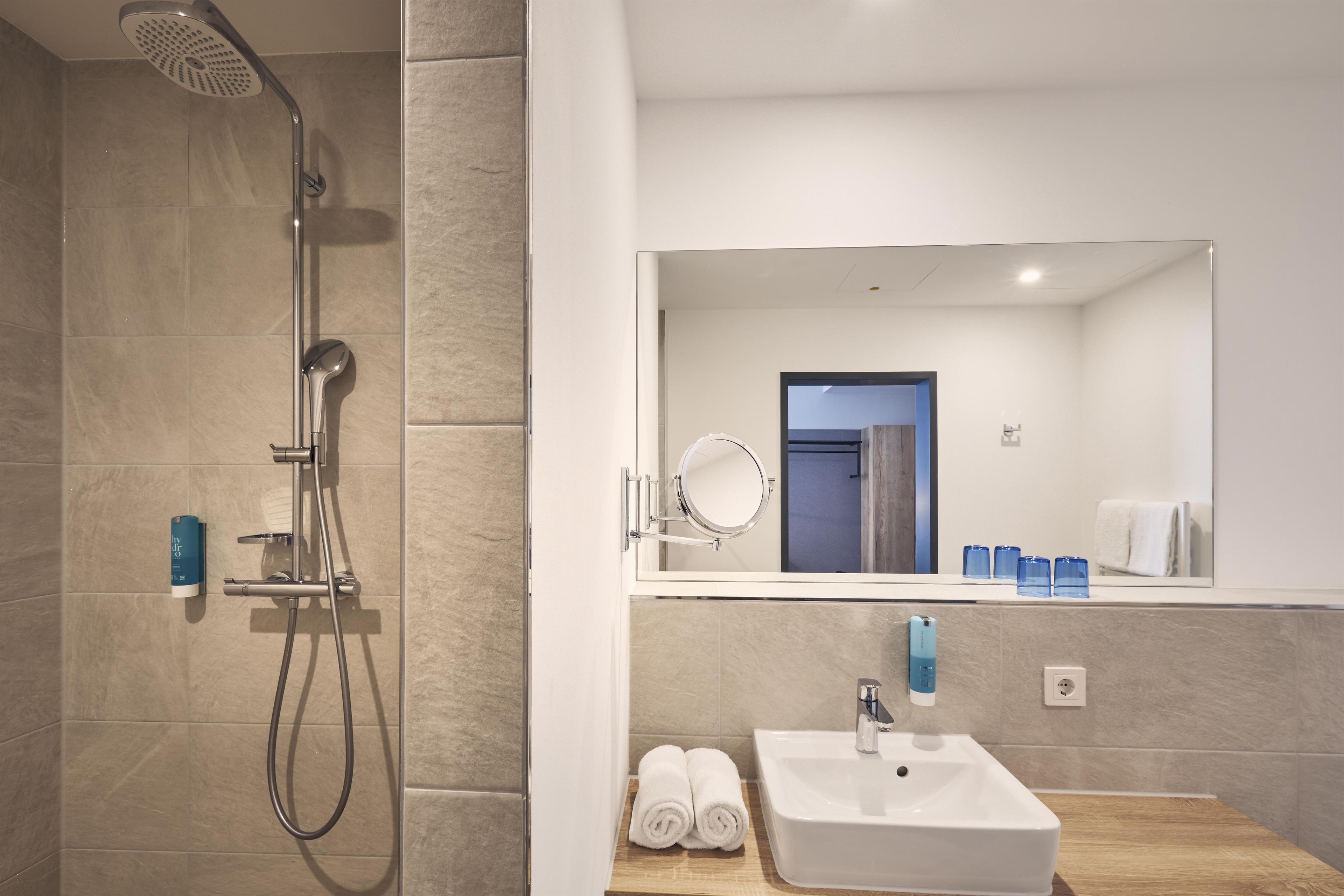 A modern bathroom with a shower, a sink, and a mirror.
