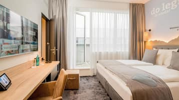 Ein Hotelzimmer mit Bett, Schreibtisch, Fernseher und einem Fenster mit Vorhängen.