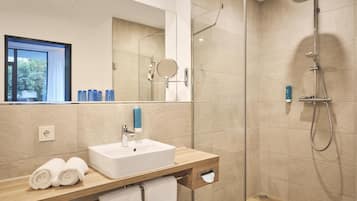 A modern bathroom with a glass shower enclosure, a sink with a mirror, and a towel rack.