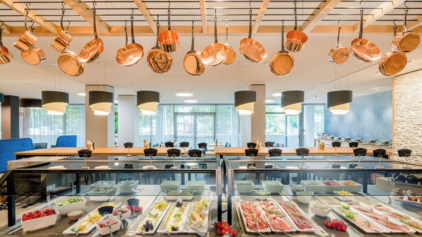 A buffet with various food items and hanging copper pots.