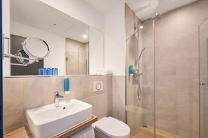 Une salle de bain moderne avec un lavabo, des toilettes et une douche à parois de verre.