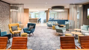 Un espace de détente moderne, doté de différents types de sièges, d’un bar et offrant une vue sur l’extérieur.
