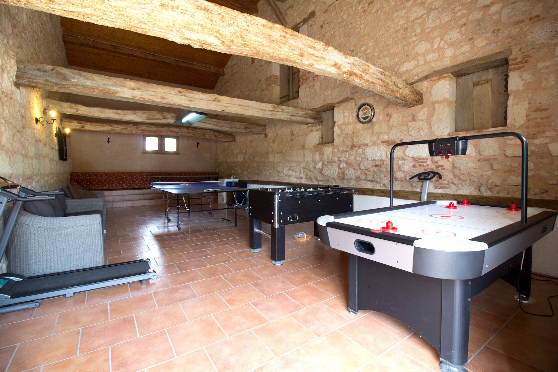 Una habitación con mesa de futbolín, mesa de ping pong y una cinta de correr.