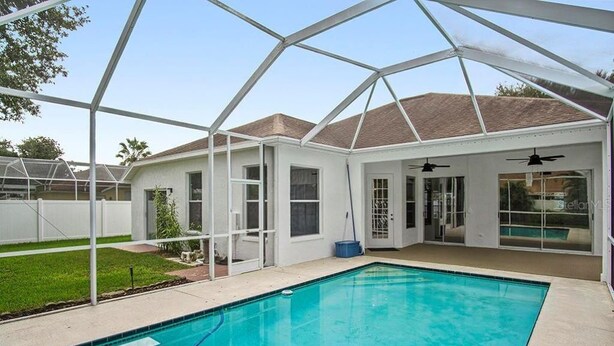 A covered outdoor swimming pool with a clear roof structure, surrounded by a white building with glass doors and windows.
