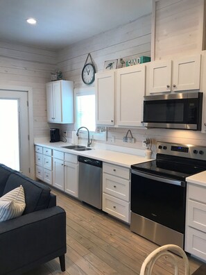 Kitchen features stainless steel appliances, a microwave, oven, and dishwasher, along with a window and a clock above the sink.