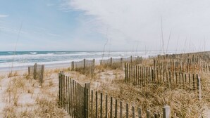Ein Strand mit Holzzaun und trockenem Gras.