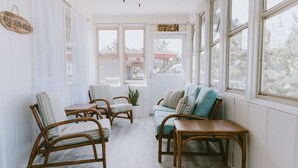 Ein Wintergarten mit Korbmöbeln, einem Türkis-sofa und Blick ins Freie.