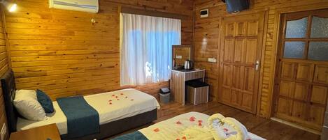 Een houten kamer in chaletstijl met twee bedden, een bureau, een spiegel en een grote kast.