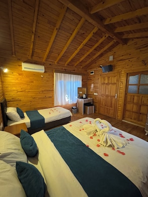 A wooden cabin-style room with two beds, a desk, a mirror, and a large wardrobe.