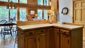 Una cocina con armarios de madera, una isla grande y vistas al exterior a través de amplios ventanales.