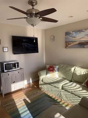 Relax in this inviting living room with a flat-screen TV, cozy couch, and a beautiful beach scene painting.