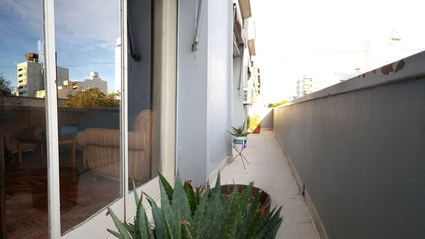 A narrow balcony with a potted aloe vera plant, a small table, and a chair. - Habitación Privada // Casa (DRN)