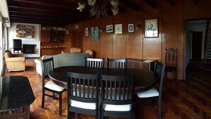 A dining area with a round table and chairs, wooden walls, and a chandelier. - Habitación Privada // Casa (DRN)
