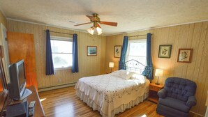 A bedroom with a bed, a chair, a desk with a television, and a ceiling fan. - This welcoming home is great for small families. (Duck)