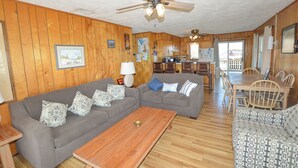 A spacious living room with a gray sectional sofa, a wooden coffee table, and a ceiling fan. - This welcoming home is great for small families. (Duck)