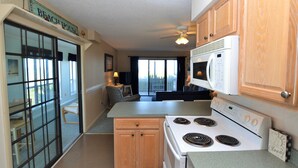 A compact kitchen with a stove, microwave, and wooden cabinets. - Charming first floor condo in Duck! (Duck)