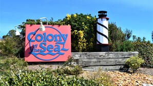 A sign for 'Colony by the Sea' with a lighthouse and wooden fence. - Charming first floor condo in Duck! (Duck)