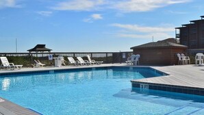 A clear blue pool with white lounge chairs and a wooden deck. - Charming first floor condo in Duck! (Duck)