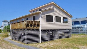 Une maison à deux étages avec une terrasse en bois et une clôture en métal.