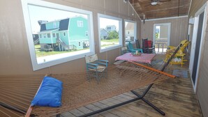Une pièce avec un hamac, un coussin bleu et une vue sur les maisons, visible à travers de grandes fenêtres.
