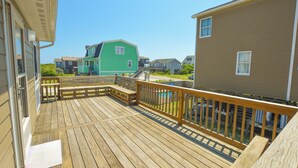 Une terrasse en bois avec une rambarde, un banc et une vue sur les maisons voisines.