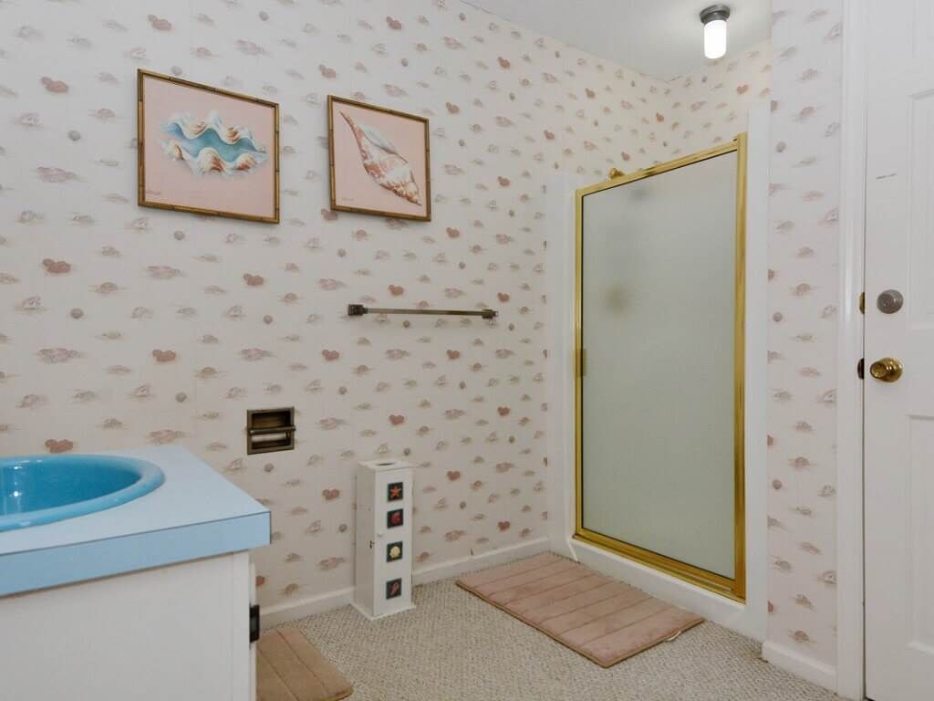 A bathroom with a shower, a sink, and two framed pictures on the wall.