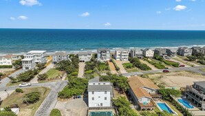 A coastal residential area with houses, a swimming pool, and a view of the ocean.