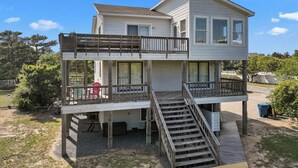A two-story house with a wooden deck and a staircase leading to the upper level.