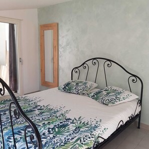 Un dormitorio con cama, ventana con cortinas y puerta.