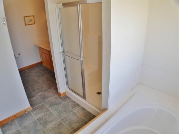 A bathroom with a glass shower enclosure, a bathtub, and a tiled floor.
