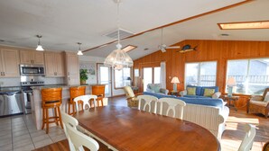 A spacious kitchen with wooden cabinets, a large dining table, and a seating area with a sofa and chairs. - Awesome 'D' has a hot tub for your family vacation entertainment (South Nags Head)