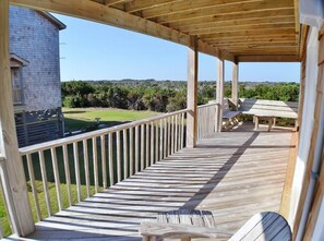 Une terrasse en bois dotée d’une rambarde, de bancs et offrant une vue sur un bâtiment et un paysage.